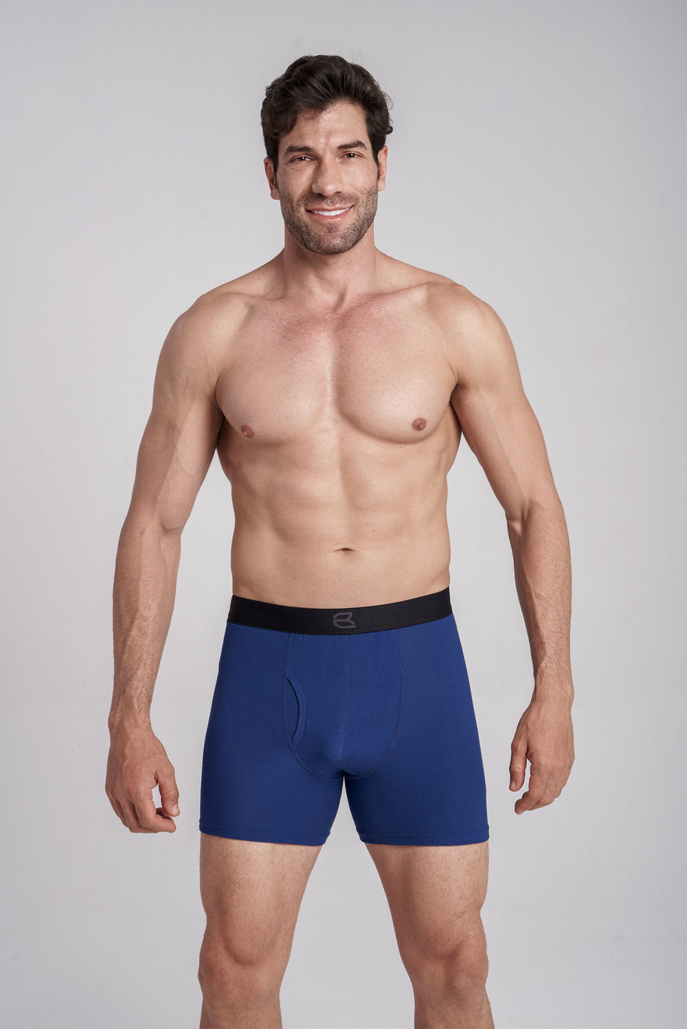 Man wearing blue boxer briefs, smiling and posing